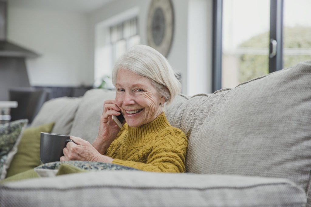 Woman applying for aged care assistance on the phone with cup of tea